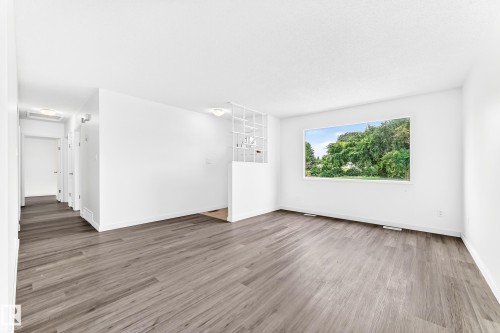 Spacious room with wood-finish flooring and a large window - 5519 142 Avenue Nw, Edmonton, AB - Indoor