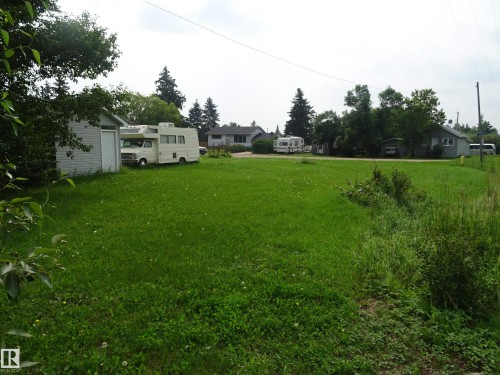 Expansive green lawn with mature trees bordering the property - 5140 51 Avenue, Vilna, AB 