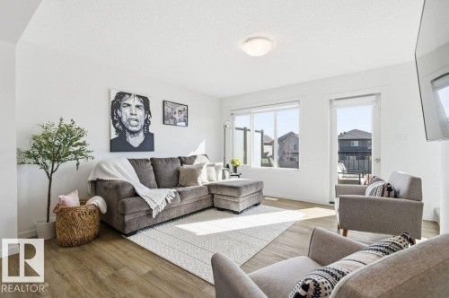 Open-concept living area featuring wood-finish flooring, white walls, and a ceiling-mounted light fixture - #49 850 Secord Bv Nw, Edmonton, AB - Indoor Photo Showing Living Room
