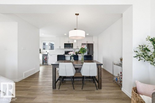 Spacious dining area featuring wood-finish flooring, a contemporary drum pendant light, and a clear sightline to the kitchen - #49 850 Secord Bv Nw, Edmonton, AB - Indoor Photo Showing Dining Room