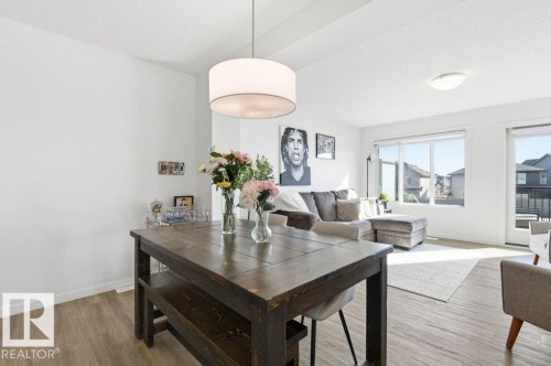 Open-concept dining and living area featuring wood-finish flooring, recessed lighting, and large windows - #49 850 Secord Bv Nw, Edmonton, AB - Indoor
