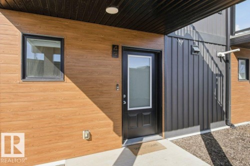 Contemporary exterior featuring horizontal wood-finish siding and vertical dark metal paneling - #49 850 Secord Bv Nw, Edmonton, AB - Outdoor With Deck Patio Veranda With Exterior