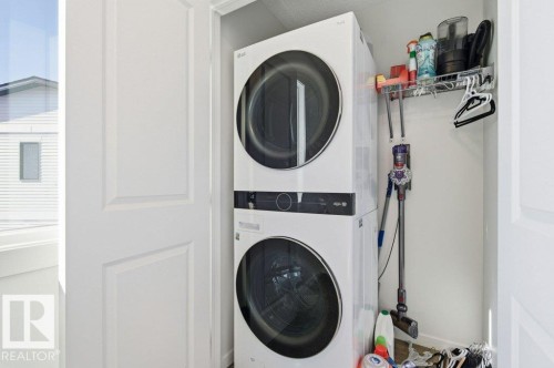 Dedicated laundry closet featuring a stacked washer and dryer unit - #49 850 Secord Bv Nw, Edmonton, AB - Indoor Photo Showing Laundry Room