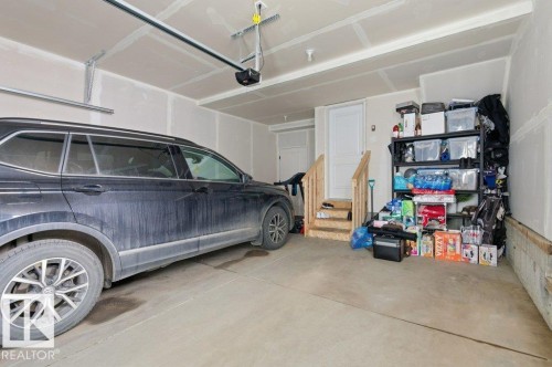Spacious garage featuring concrete flooring and a built-in overhead garage door opener - #49 850 Secord Bv Nw, Edmonton, AB - Indoor Photo Showing Garage