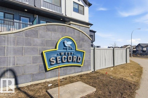 Community entrance sign featuring a block construction base and a blue and yellow emblem - #49 850 Secord Bv Nw, Edmonton, AB - Outdoor