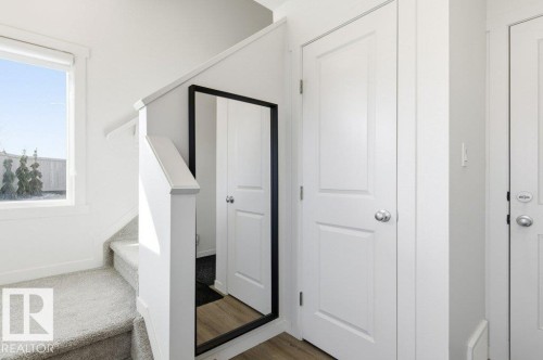 Carpeted staircase with white balustrade and handrail, featuring a prominent window - #49 850 Secord Bv Nw, Edmonton, AB - Indoor Photo Showing Other Room