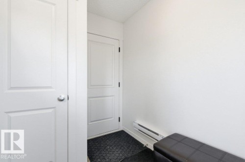 Entryway featuring white paneled doors, white walls, and baseboard heating - #49 850 Secord Bv Nw, Edmonton, AB - Indoor Photo Showing Other Room
