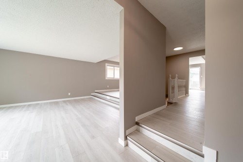 Split-level interior featuring contemporary light wood-finish flooring, neutral wall tones, and white trim throughout - 6907 19 Avenue Nw, Edmonton, AB - Indoor Photo Showing Other Room
