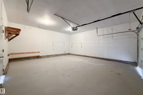 Spacious garage featuring a concrete floor, white walls, and an overhead garage door opener - 6907 19 Avenue Nw, Edmonton, AB - Indoor Photo Showing Garage