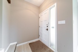 Entryway featuring a paneled door with a frosted sidelight, light wood-finish flooring, and neutral wall tones - 