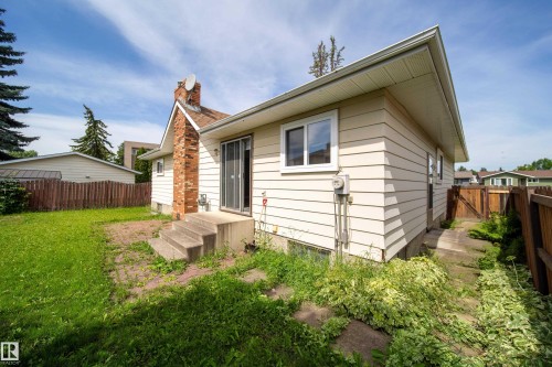 Rear exterior featuring cream horizontal siding and a red brick chimney - 6907 19 Avenue Nw, Edmonton, AB - Outdoor