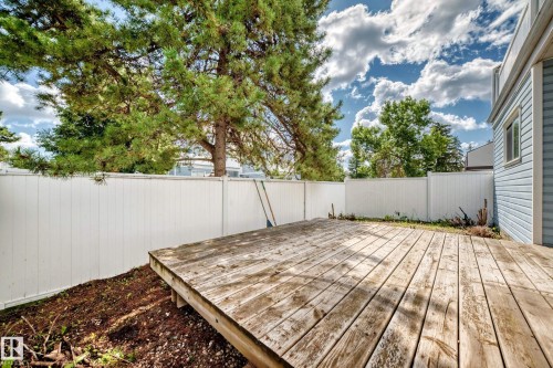 Spacious backyard oasis featuring a composite deck with clean lines, mature shade trees, and a white vinyl privacy fence - 290 Lancaster Terrace Nw, Edmonton, AB - Outdoor With Deck Patio Veranda