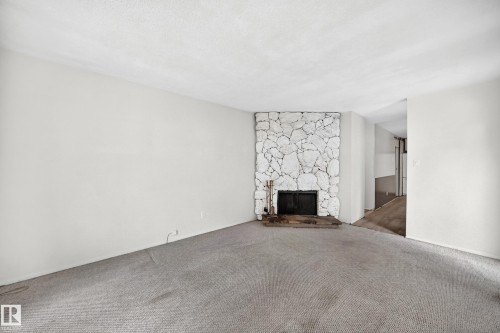 Stone-clad fireplace with a black firebox and hearth - 290 Lancaster Terrace Nw, Edmonton, AB - Indoor Photo Showing Other Room With Fireplace