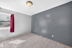 Spacious room featuring light gray carpet flooring, a window with white trim, and a ceiling-mounted light fixture - 
