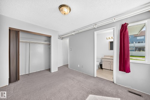 Carpeted room with a full closet featuring bi-fold doors - 290 Lancaster Terrace Nw, Edmonton, AB - Indoor