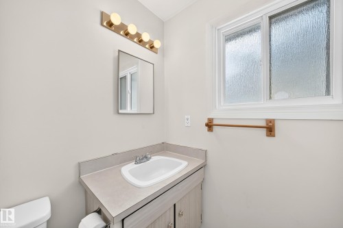 Bathroom vanity with integrated sink, laminate countertop, and wood-finish cabinetry - 290 Lancaster Terrace Nw, Edmonton, AB - Indoor Photo Showing Bathroom