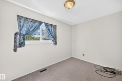 Bright interior room featuring a window with natural light, light-colored walls, and a ceiling-mounted light fixture - 
