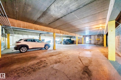 Concrete parking garage featuring exposed concrete ceilings and support beams, illuminated overhead lighting, and ample space - 290 Lancaster Terrace Nw, Edmonton, AB - Indoor Photo Showing Garage