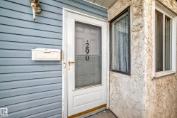 Welcoming entry featuring a white-framed storm door with brass hardware and address numerals, set within horizontal siding in soft blue-gray tones - 