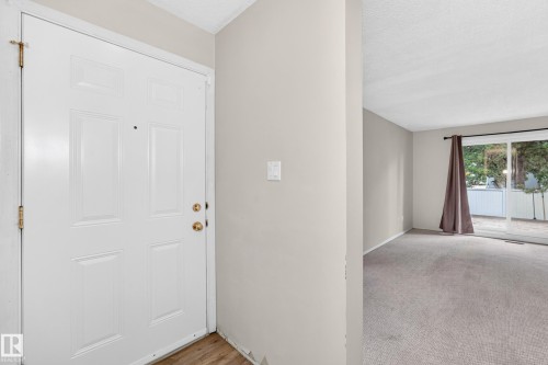 Welcoming entry foyer featuring a six-panel white painted door with brass hardware, neutral wall finishes, and wood-finish flooring - 290 Lancaster Terrace Nw, Edmonton, AB - Indoor Photo Showing Other Room