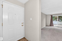 Welcoming entry foyer featuring a six-panel white painted door with brass hardware, neutral wall finishes, and wood-finish flooring - 