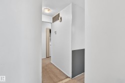Hallway featuring light-colored carpet, a ceiling-mounted light fixture, and a white wall with a gray lower section - 