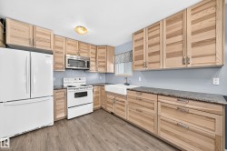 Kitchen featuring natural wood cabinetry, dark speckled countertops, and wood-finish flooring - 