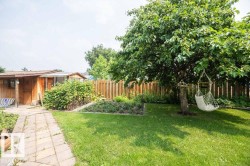 Expansive backyard featuring a manicured lawn, established trees, and a stone paver pathway - 