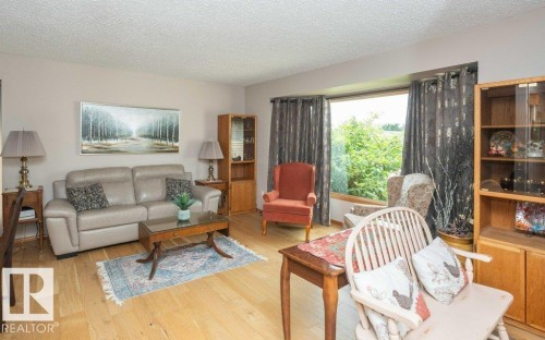 Bright living area featuring wood-finish flooring, a large bay window, and neutral wall tones - 10711 108 Avenue, Westlock, AB - Indoor Photo Showing Living Room