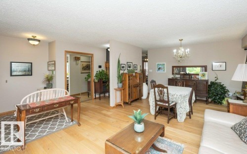 Open-concept common area featuring wood-finish flooring, a traditional chandelier, and neutral wall tones - 10711 108 Avenue, Westlock, AB - Indoor Photo Showing Living Room