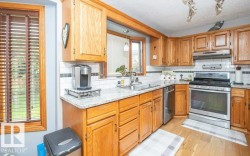 Kitchen featuring abundant wood cabinetry, light-toned countertops, stainless steel appliances, a tile backsplash, and wood-finish flooring - 