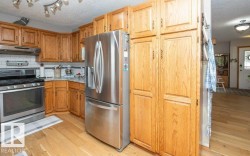 Kitchen featuring wood-finish cabinetry, stainless steel appliances, a tile backsplash, and light wood-finish flooring - 