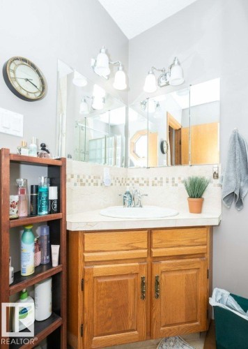Vanity with light wood-finish cabinetry, a single basin sink, and a light-toned countertop - 10711 108 Avenue, Westlock, AB - Indoor Photo Showing Bathroom