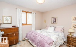 Bedroom featuring neutral wall tones, wood-trimmed window with blinds and patterned curtains, and textured ceiling - 