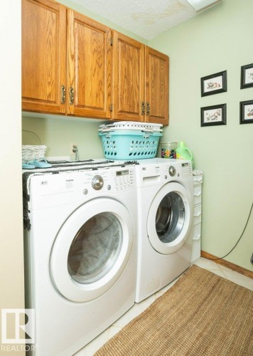 Dedicated laundry area featuring overhead wood cabinetry - 10711 108 Avenue, Westlock, AB - Indoor Photo Showing Laundry Room