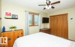 Bedroom featuring a ceiling fan with integrated lighting, wood-finish bi-fold closet doors, a window with horizontal blinds, and light-toned walls - 