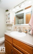 Bathroom vanity featuring a light-toned countertop, an integrated oval sink, and a chrome faucet - 