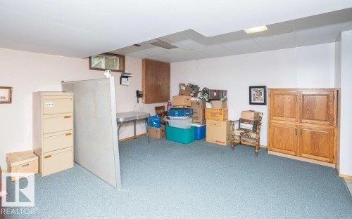 Spacious room featuring light blue carpeting, light-colored walls, and a drop ceiling with recessed lighting - 10711 108 Avenue, Westlock, AB - Indoor