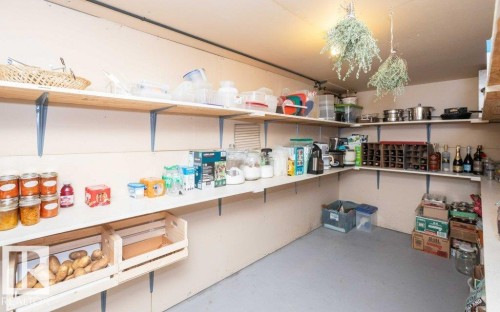 Expansive pantry featuring extensive shelving, corner storage, integrated wooden crate storage, and concrete flooring - 10711 108 Avenue, Westlock, AB - Indoor Photo Showing Other Room
