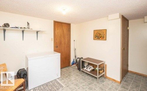 Utility room featuring white walls, textured ceilings, durable tile flooring, and two wood-finish doors - 10711 108 Avenue, Westlock, AB - Indoor Photo Showing Other Room