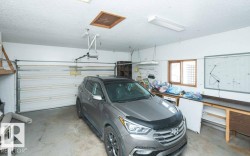 Spacious garage with an overhead door, automatic opener, workbench, pegboard storage, and a window for natural light - 
