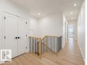 Upper-level hallway featuring light wood-finish flooring, recessed lighting, white walls, and contemporary doors with matte black hardware - 3320 Chickadee Drive Nw, Edmonton, AB  - Indoor Photo Showing Other Room 