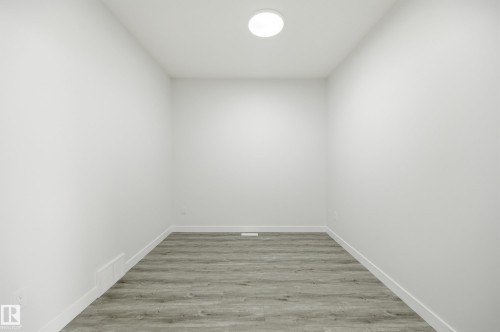 Room with neutral white walls, grey wood-finish flooring, white baseboards, and a flush-mount ceiling light fixture - 3 Pierwyck Loop, Spruce Grove, AB - Indoor Photo Showing Other Room