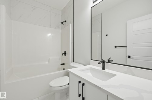 Bathroom featuring a white bathtub with a shower, white tile surround, and matte black fixtures - 3 Pierwyck Loop, Spruce Grove, AB - Indoor Photo Showing Bathroom