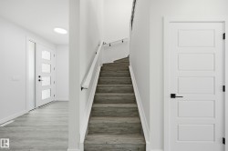 Staircase featuring wood-finish treads and a white handrail with black supports - 