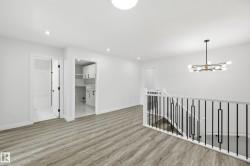 Upper-level landing featuring wood-finish flooring, recessed lighting, and a modern chandelier - 
