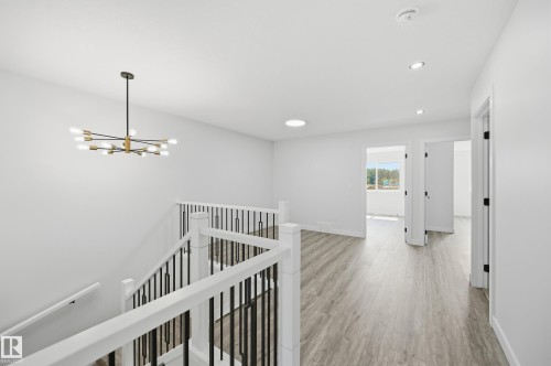 Upper-level landing featuring wood-finish flooring, a contemporary chandelier, recessed lighting, and a white and black stair railing - 3 Pierwyck Loop, Spruce Grove, AB - Indoor Photo Showing Other Room
