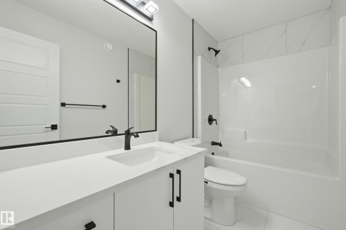 Contemporary bathroom featuring a white vanity with integrated sink, matte black hardware, and a framed mirror - 3 Pierwyck Loop, Spruce Grove, AB - Indoor Photo Showing Bathroom