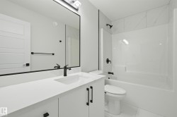 Contemporary bathroom featuring a white vanity with integrated sink, matte black hardware, and a framed mirror - 