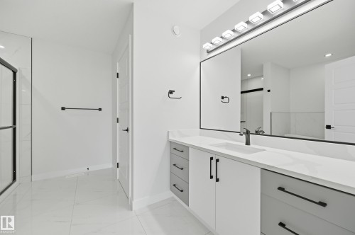 Modern bathroom featuring a double vanity with stone-finish countertops, black matte fixtures, and a spacious walk-in shower with a glass enclosure - 3 Pierwyck Loop, Spruce Grove, AB - Indoor